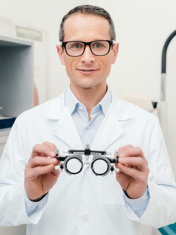 portrait-of-optometrist-in-white-coat-holding-trial-frame-in-hands-in-clinic.jpg