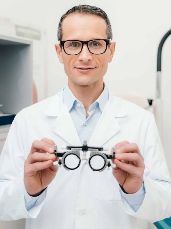 portrait-of-optometrist-in-white-coat-holding-trial-frame-in-hands-in-clinic.jpg